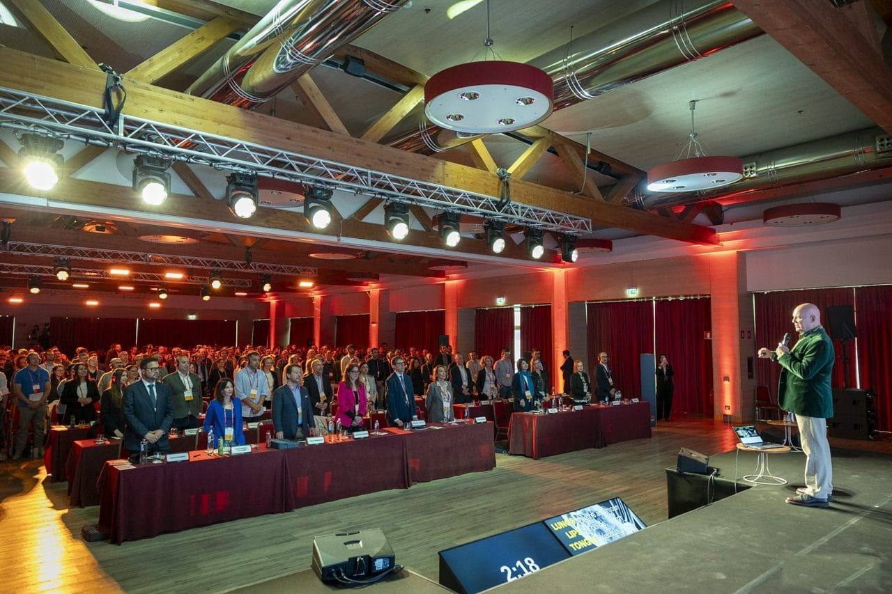A wide view of a large hall full of delegates, with Julian Treasure speaking at the front